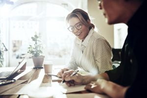 smiling-coworkers-discussing-notes-at-a-table-in-J7E2BL3